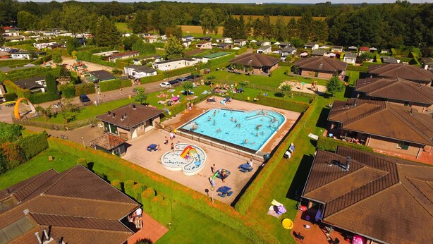 A residential area with a swimming pool, houses, and a playground.