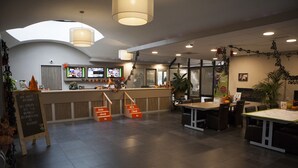 A modern interior with a reception desk, seating area, and a staircase leading to an upper level.