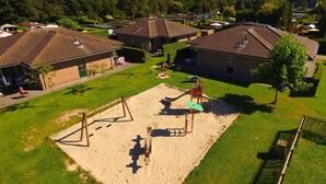 A residential area with houses, a playground, and a well-maintained lawn.