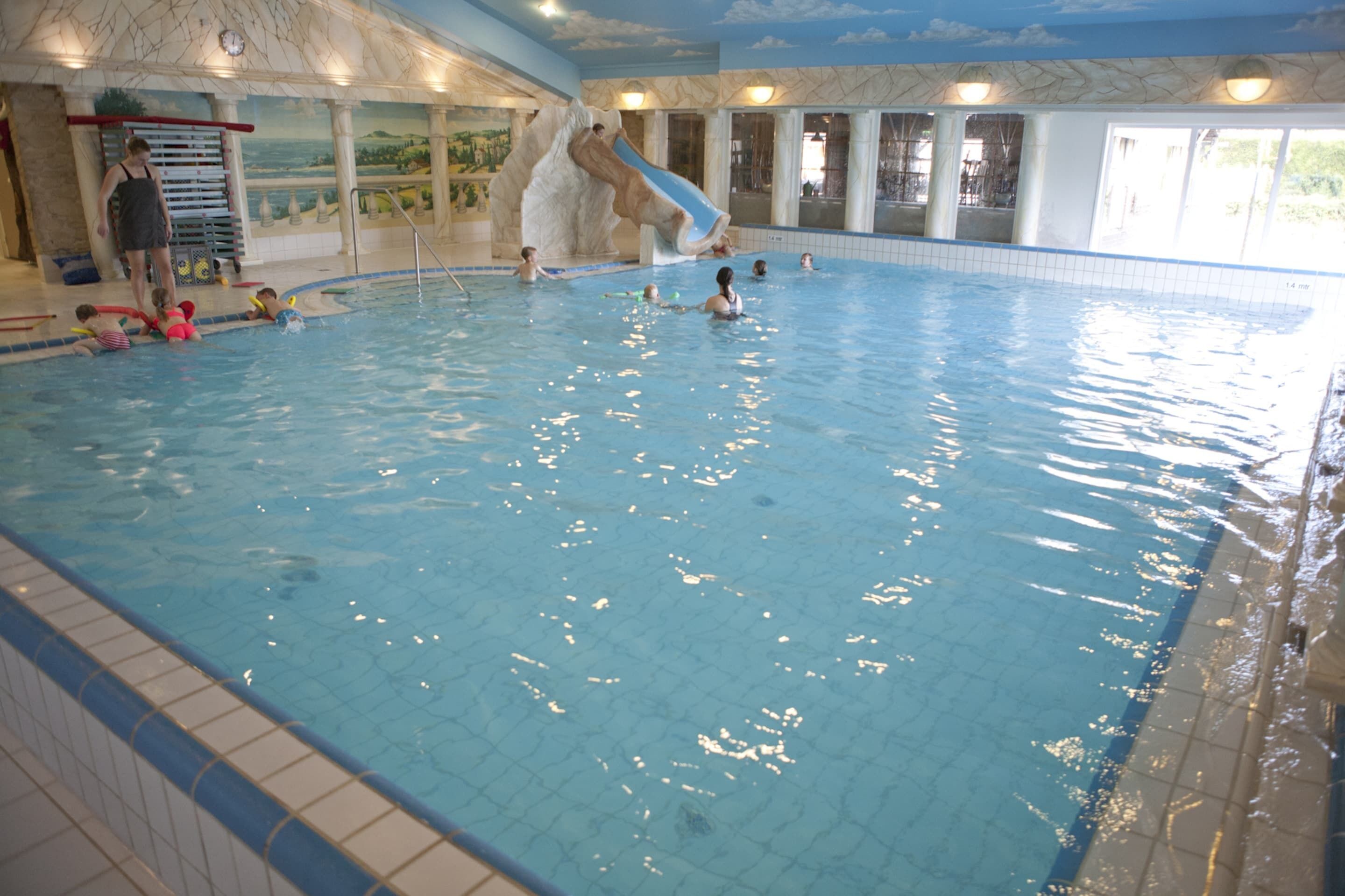 Ein Hallenbad mit Rutsche und Rettungsschwimmerstand.