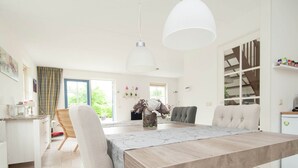 A modern kitchen with a dining area, featuring a wooden table, chairs, and pendant lighting. - Holiday Home in Schoorl with Fenced Garden near Dunes (Schoorl)