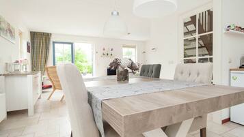 A modern kitchen with a dining area, featuring a wooden table, chairs, and pendant lighting.