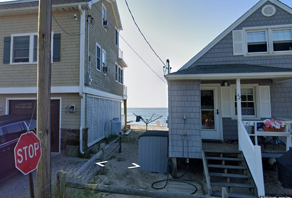 Ein Küstenhaus mit Veranda, einem Stoppschild und Blick auf den Strand.