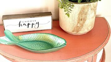 Una mesa redonda pequeña con un plato verde con forma de pez y un letrero que dice 'CHOOSE happy'.
