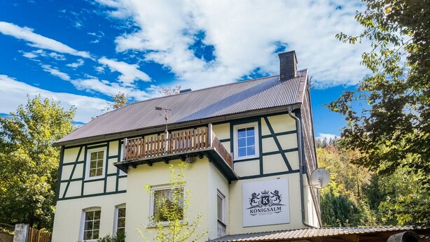 Un edificio tradicional de entramado de madera con un letrero que dice "Königsalm".