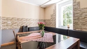 Un comedor con mesa de vidrio, asientos acolchados negros y una pared de acento de piedra.