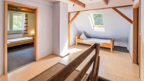 Un dormitorio con techo inclinado, vigas de madera y tragaluces, con dos camas.