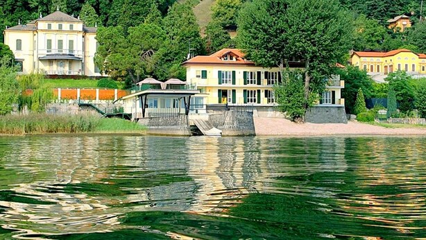 A lakeside property with multiple buildings, a dock, and lush greenery. - Holiday Home in Meina With Private Beach (Meina)