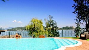 A swimming pool with a view of a lake and hills in the background. - Holiday Home in Meina With Private Beach (Meina)