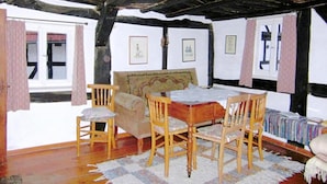 Ein traditionell eingerichteter Raum mit einem Holztisch und -stühlen, einem Bett mit floralem Kopfteil und einem gemusterten Teppich.