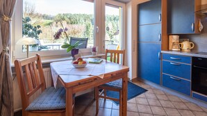 A kitchen with a dining table, chairs, and a view of a garden. - Apartment in the Odenwald With Terrace (Mossautal)