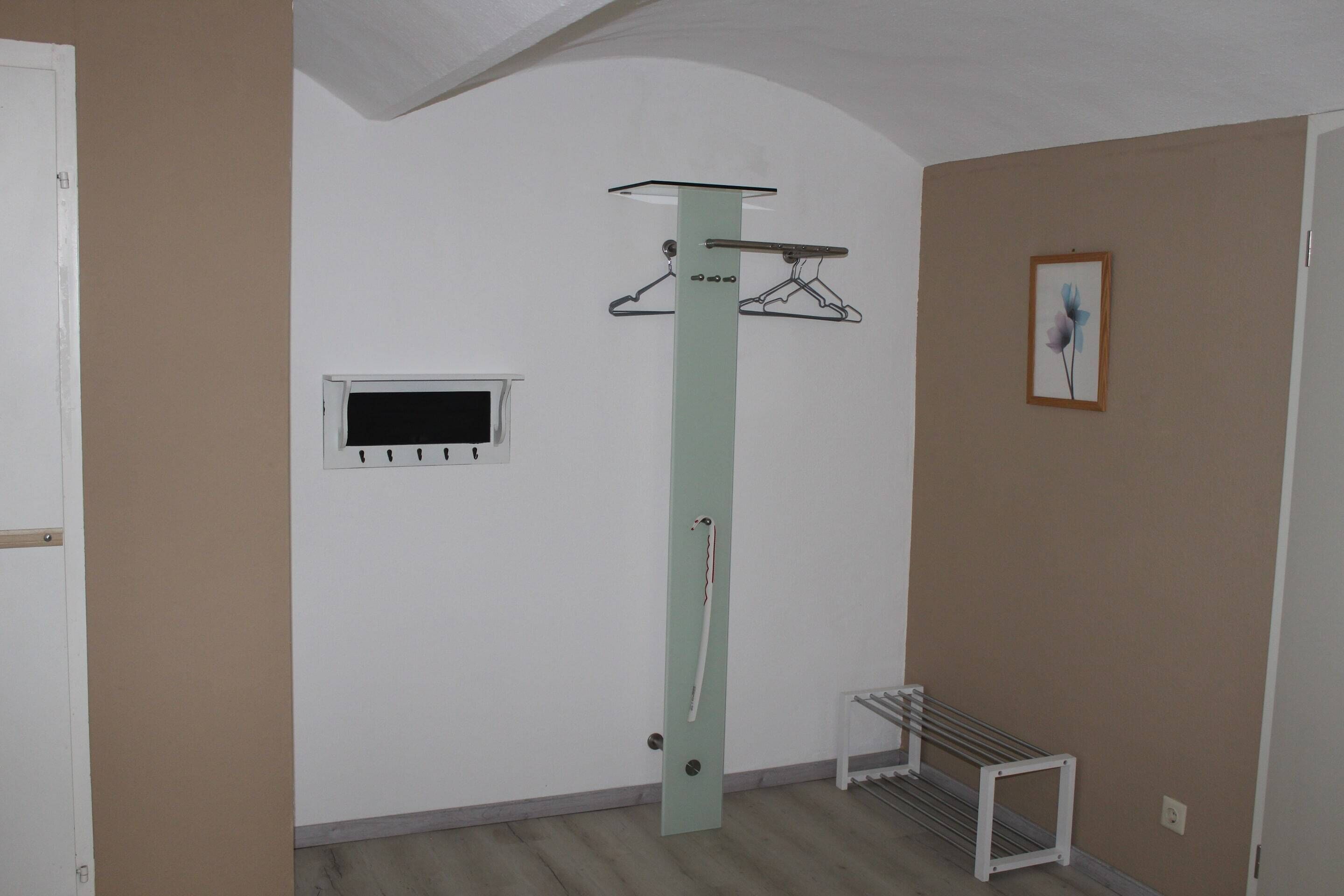 A room with a white door, a coat rack, a small window, and a radiator.