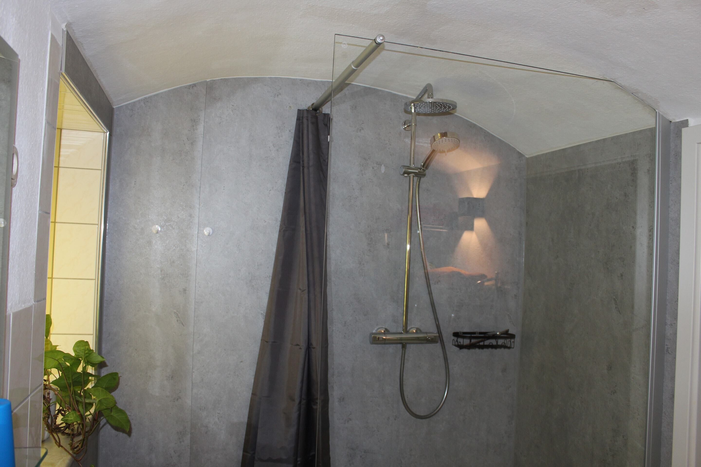 A shower with a glass door, a showerhead, and a towel rack.