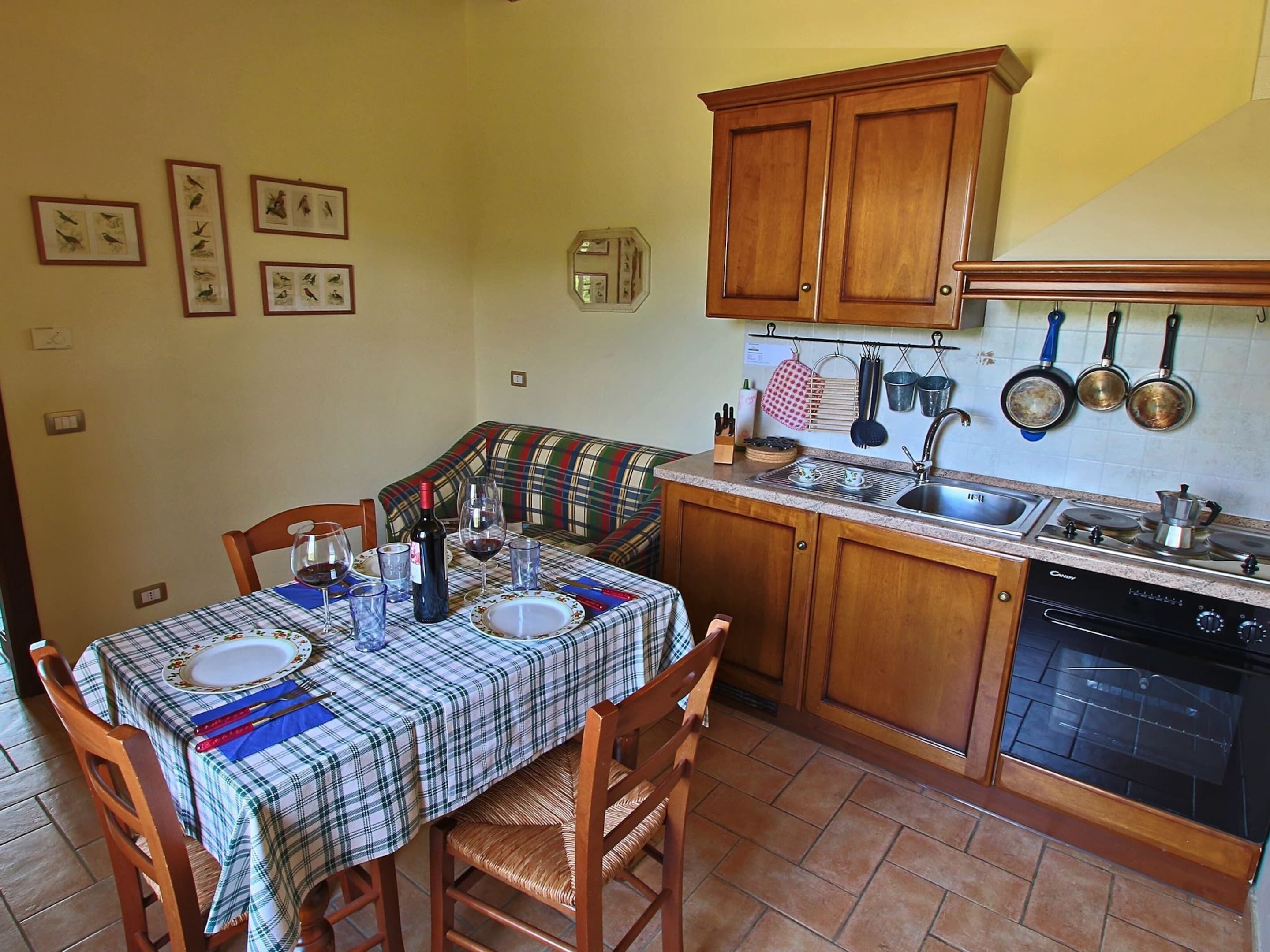 Une cuisine compacte avec des meubles en bois, une table à manger pour deux personnes et un petit coin repas agrémenté d’un canapé.