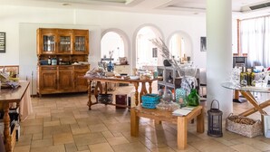 A spacious kitchen with wooden cabinets, a dining table with various items, and a view of the living area with arched windows. - Agriturismo with Pool near Golf Course & Salò (Salò)