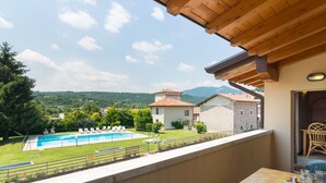 A balcony with a view of a swimming pool, a table with chairs, and a mountainous landscape in the background. - Agriturismo with Pool near Golf Course & Salò (Salò)