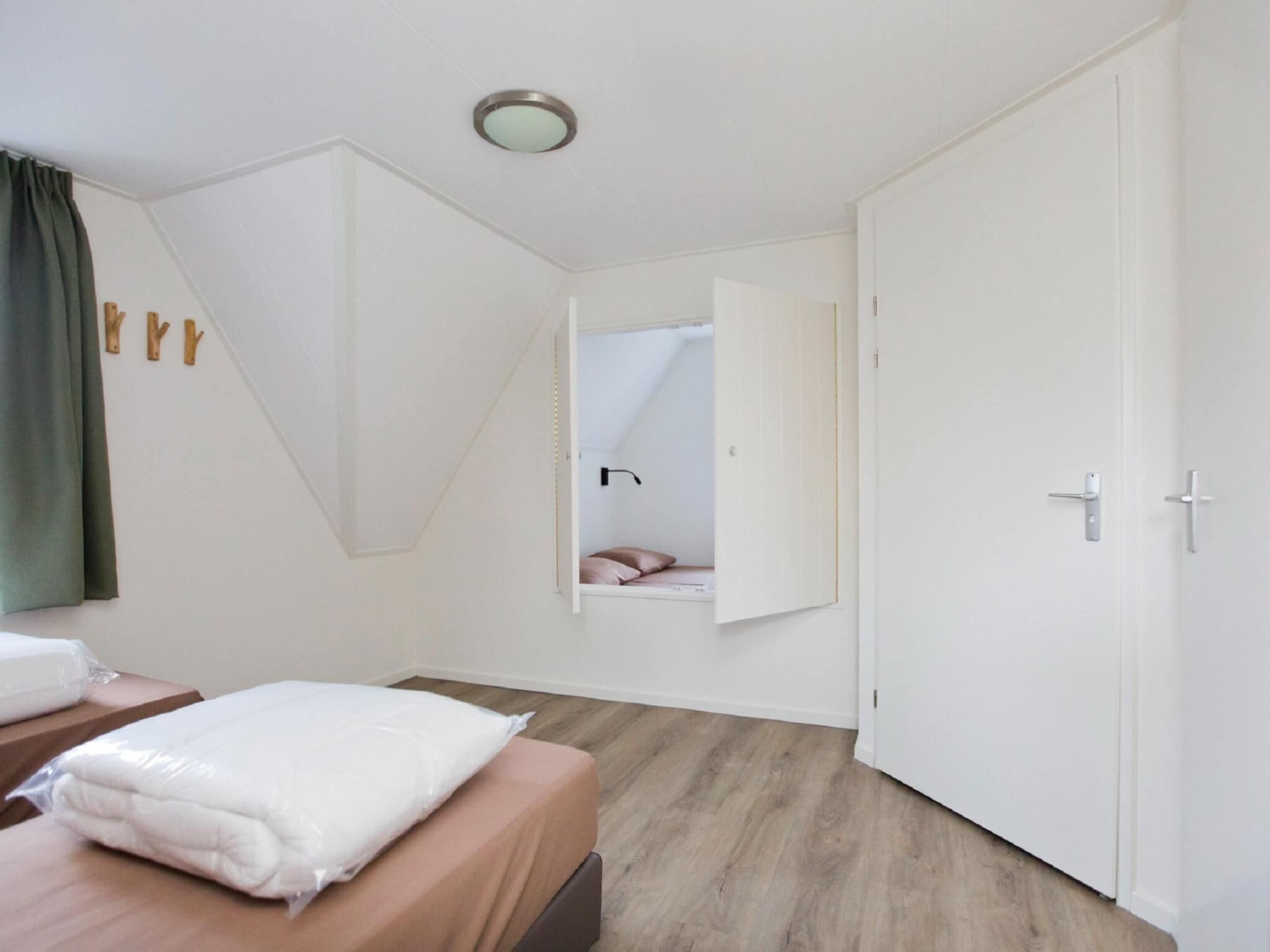 Una habitación de hotel con cama, mesita de noche, espejo y puerta.