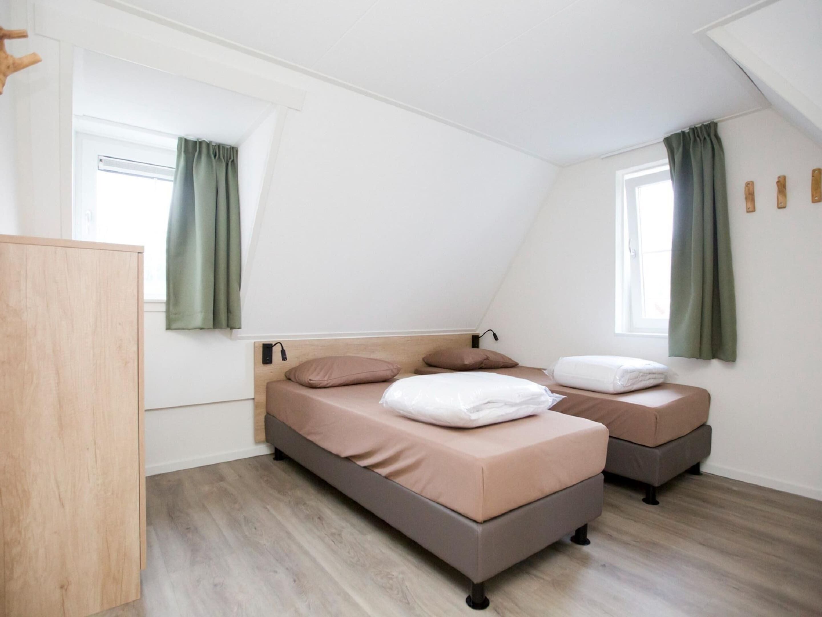 Une chambre avec un lit en mezzanine, un bureau et une armoire.