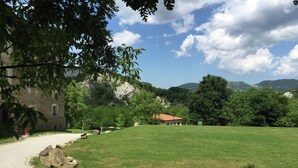 A rural landscape with a stone building, a red-roofed structure, and a grassy field. - Apartment in Marche With Pool Access (Apecchio)