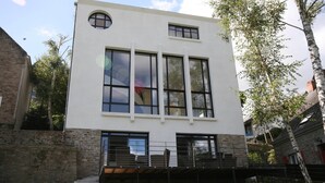 A modern two-story building with large windows, a stone base, and a balcony. - Luxurious Villa in Pont-aven With Private Pool (Pont-Aven)