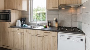 Una cocina moderna con armarios de madera, horno empotrado, lavavajillas y ventana que proporciona luz natural.