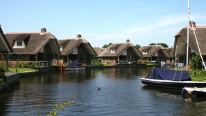 Un canal con casas a un lado y un bote amarrado al otro.