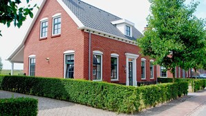 A red brick house with a gabled roof, white trim, and multiple windows. - Holiday Home in Colijnsplaat by the Sea (Colijnsplaat)