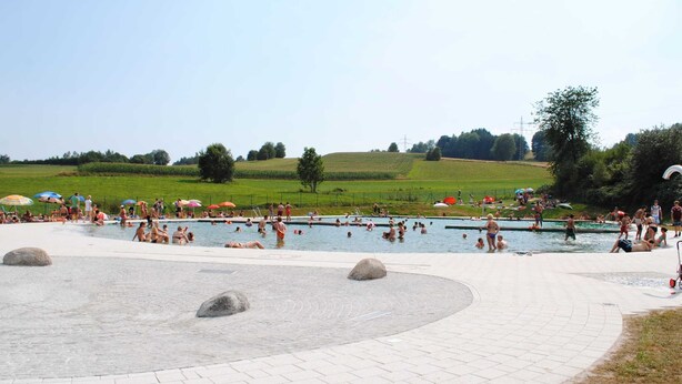 A public swimming pool with a paved walkway and large rocks. - Relaxing Apartment With Sauna (Ruhmannsfelden)