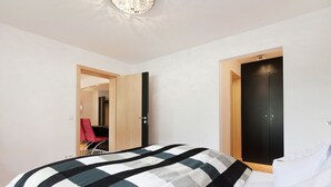 A bedroom with a bed, a desk, and a chair. There are two doors, one of which leads to a bathroom. - Relaxing Apartment With Sauna (Ruhmannsfelden)