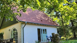 A house with a red-tiled roof, a white exterior, and a small patio with outdoor furniture. - Tidy House With Sauna and Steam Bath, in a Forest (Brandscheid)