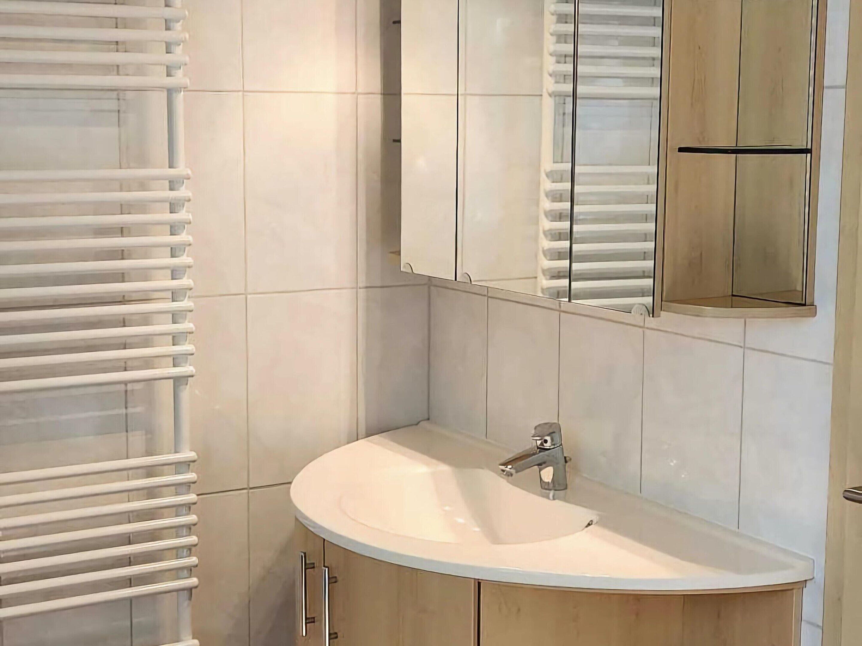 A bathroom with a white sink, a mirror, and a towel rack.