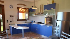 Eine Küche mit blauen Schränken, einer weißen Arbeitsplatte, einem Edelstahlkühlschrank und einem Esstisch mit Stühlen.