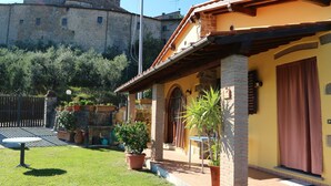 Ein Innenhof mit einem Steinhaus, Blumentöpfen und einem kleinen Tisch.