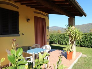 A patio with a table and chairs, a potted plant, and a view of a mountain range. - Belvilla by OYO Valleriana (Pescia)