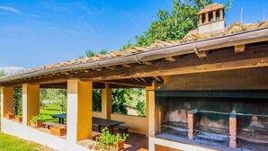 A covered outdoor patio with a brick fireplace, seating areas, and potted plants. - Rustic Farmhouse in Terricciola (Terricciola)
