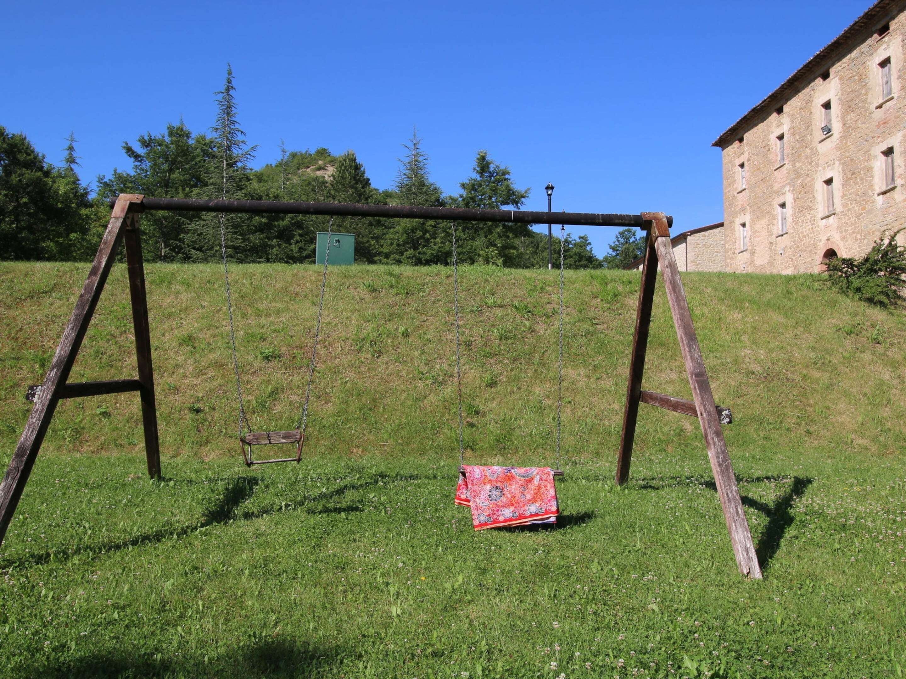 A swing set in a grassy area with a building in the background.