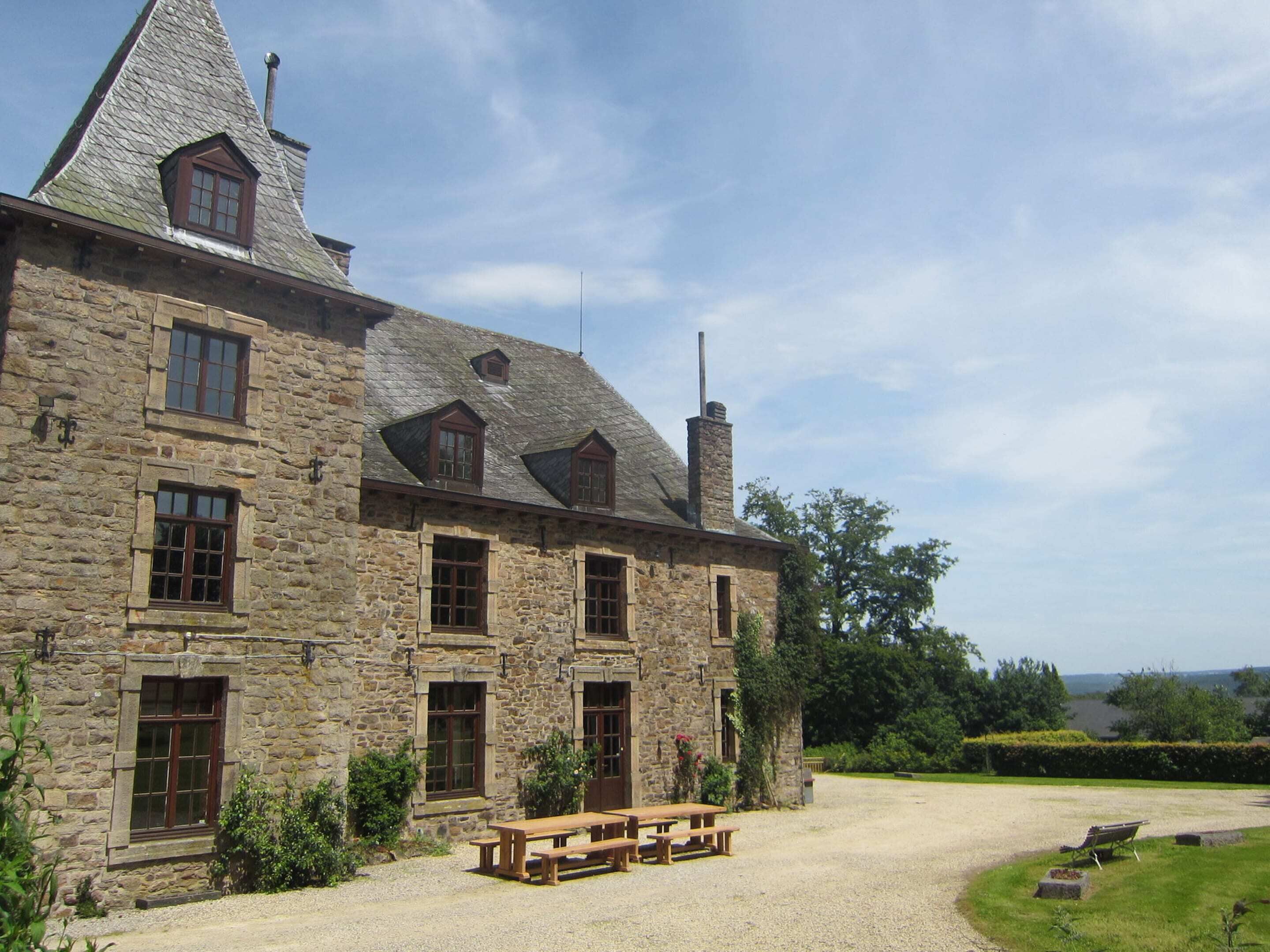 A stone building with multiple windows and a sloped roof.