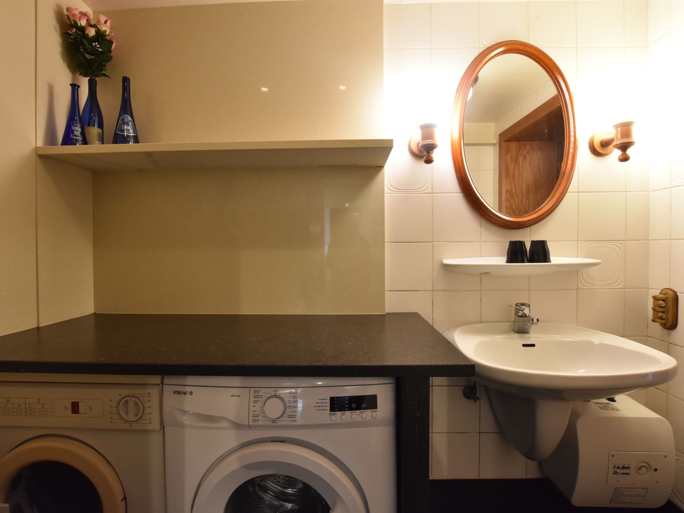 Een kleine hotelbadkamer met een wasmachine, een wastafel en een spiegel.
