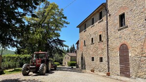 Un bâtiment en pierre avec une grande porte et de grandes fenêtres, un tracteur garé devant, et un ciel bleu dégagé.