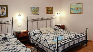 Un dormitorio con dos camas, vigas de madera en el techo y tres lámparas fijadas a la pared.