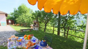 Un área de comedor al aire libre con una mesa dispuesta para una comida, rodeada de follaje y vistas del paisaje.