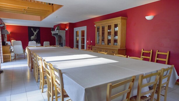Una sala da pranzo con un lungo tavolo, sedie, un armadietto e un camino.