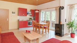 Uma cozinha moderna com armários vermelhos, sala de jantar com mobiliário de madeira e uma grande janela que proporciona luz natural.