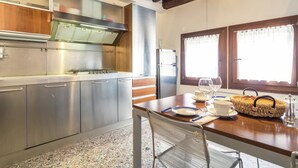 A kitchen with stainless steel appliances, a wooden table with a woven basket, and a window with curtains. - Belvilla by OYO Paradiso (Venice)