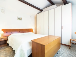 A bedroom with a bed, wooden nightstands, a wardrobe, and a small table.