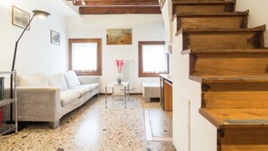 A spacious living area with a sofa, a small table with a vase, and a staircase. - Belvilla by OYO Paradiso (Venice)