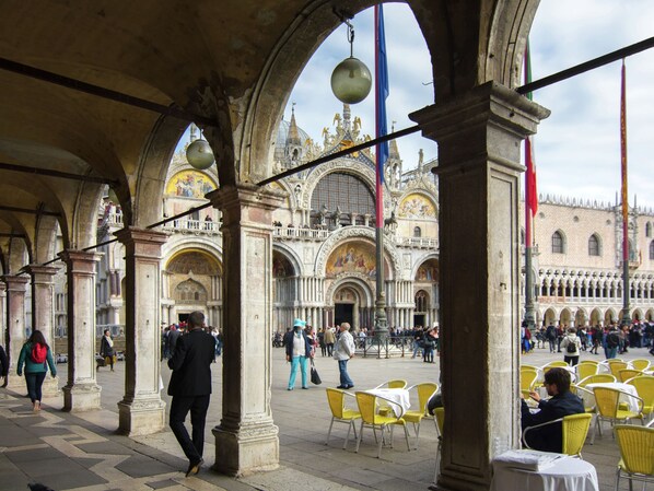 An outdoor area with stone arches, a fountain, and yellow chairs.