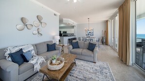 Amplia sala de estar con un conjunto de sofás, una mesa de centro y un comedor al fondo.