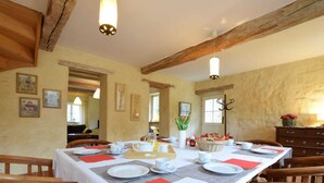 A dining area with a long table set for a meal, wooden chairs, and a chandelier. - Castle Wing Situated in the Heart of a Quiet (Manhay)
