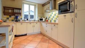 A kitchen with white cabinets, a tiled backsplash, a window, and a microwave. - Castle Wing Situated in the Heart of a Quiet (Manhay)
